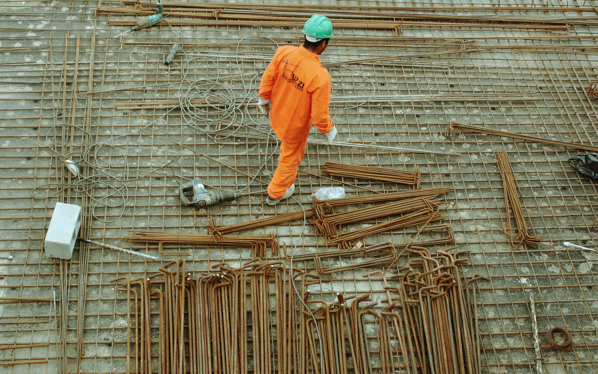 A worker crossing a reinforcing mat laid out ahead of a large concrete pour.