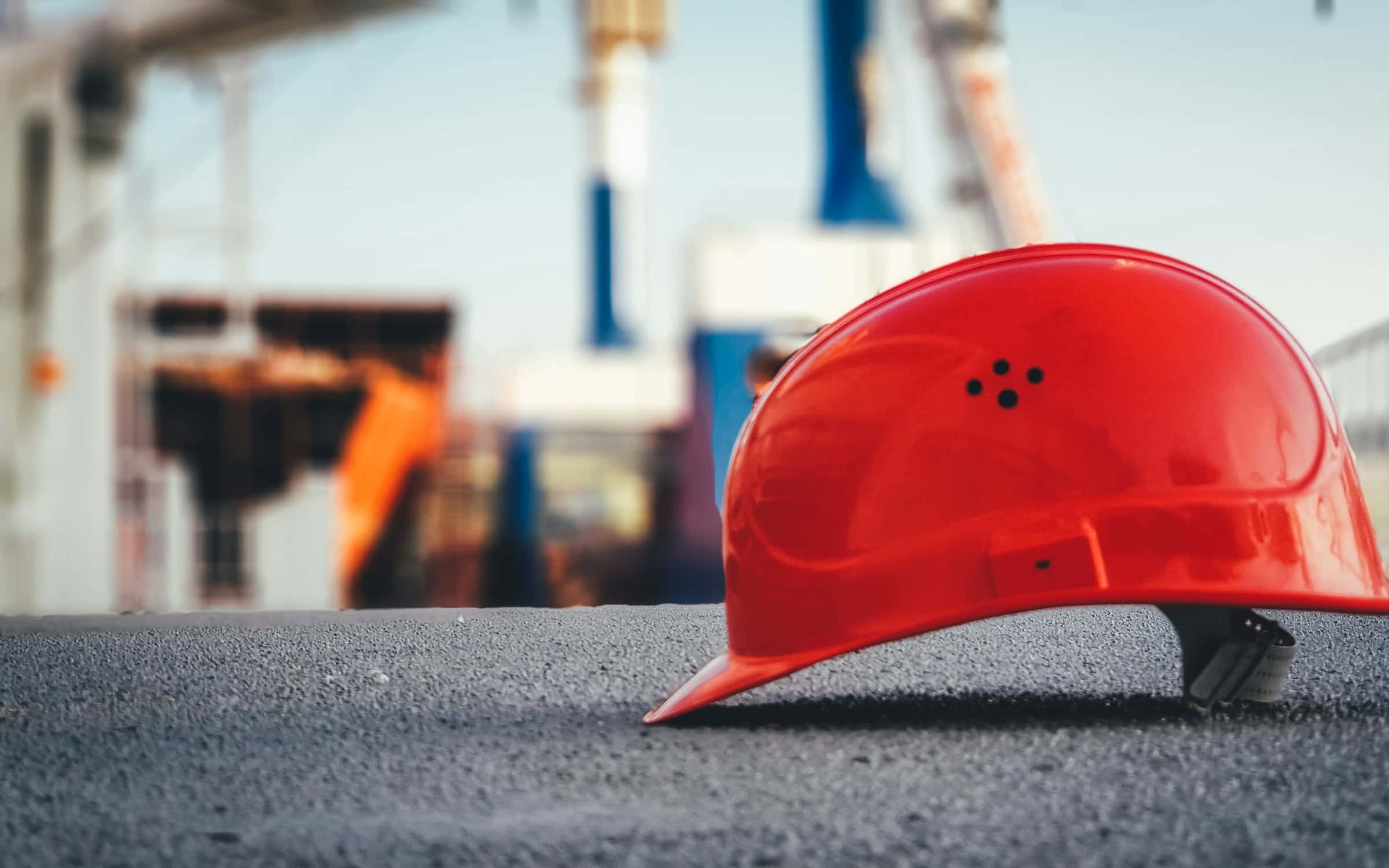A hard hat resting on a paved surface in front of an active site.