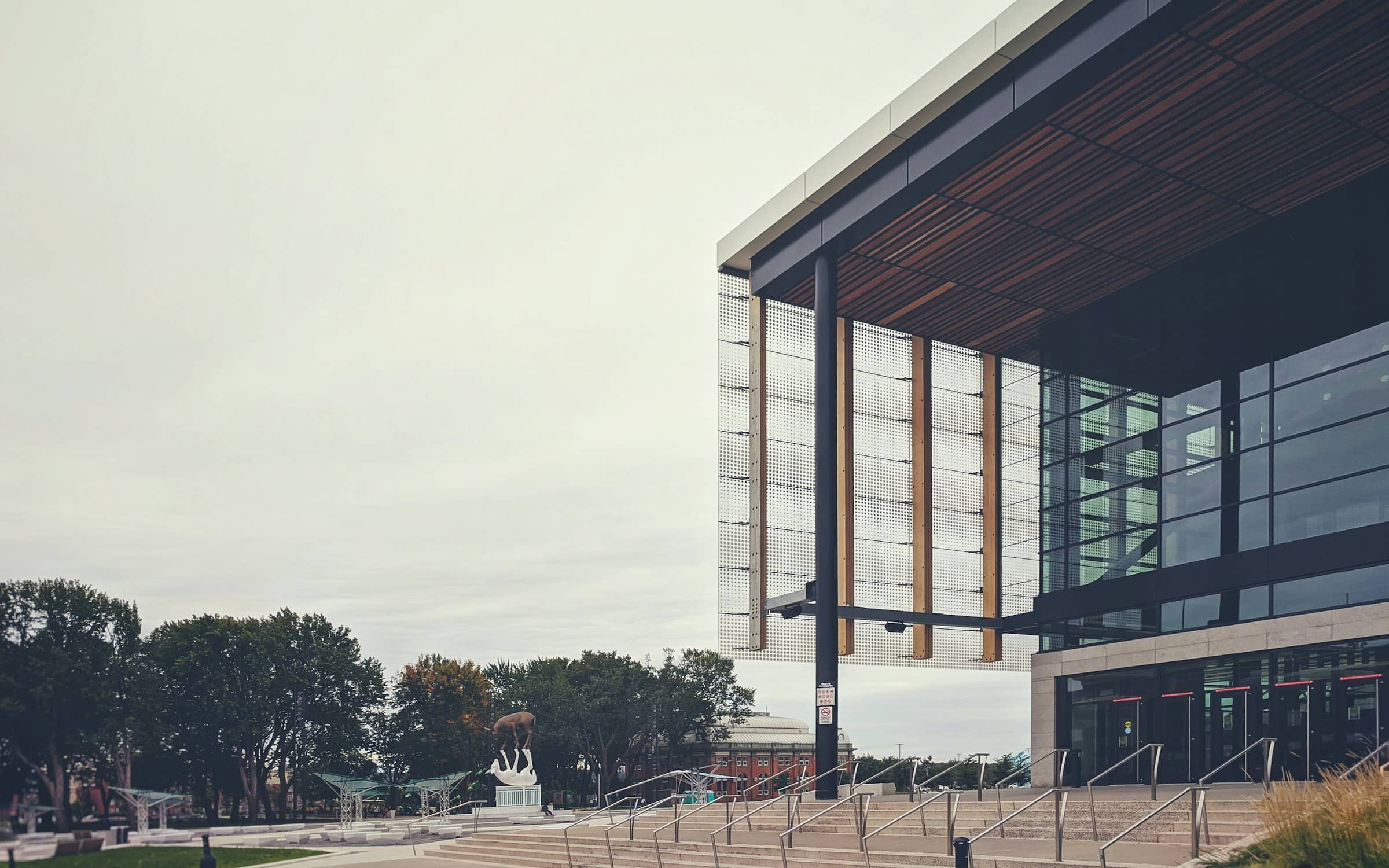 A completed civic building with a deep timber-lined canopy over its plaza and entrance steps.